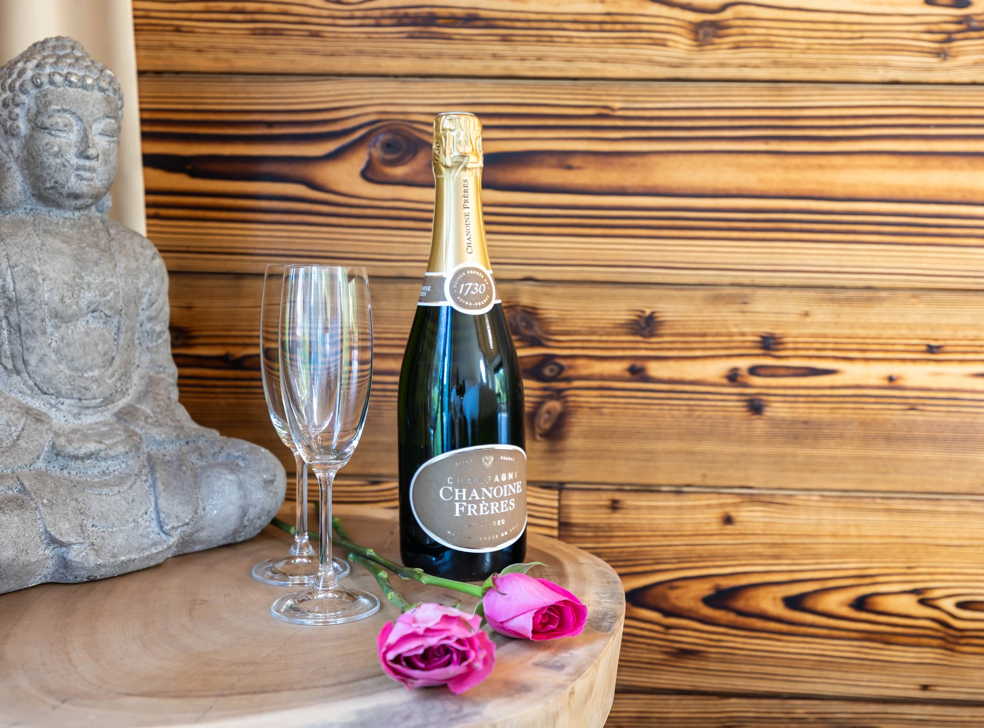 Champagne, glasses and roses beside a Buddha statue at ZenArden.
